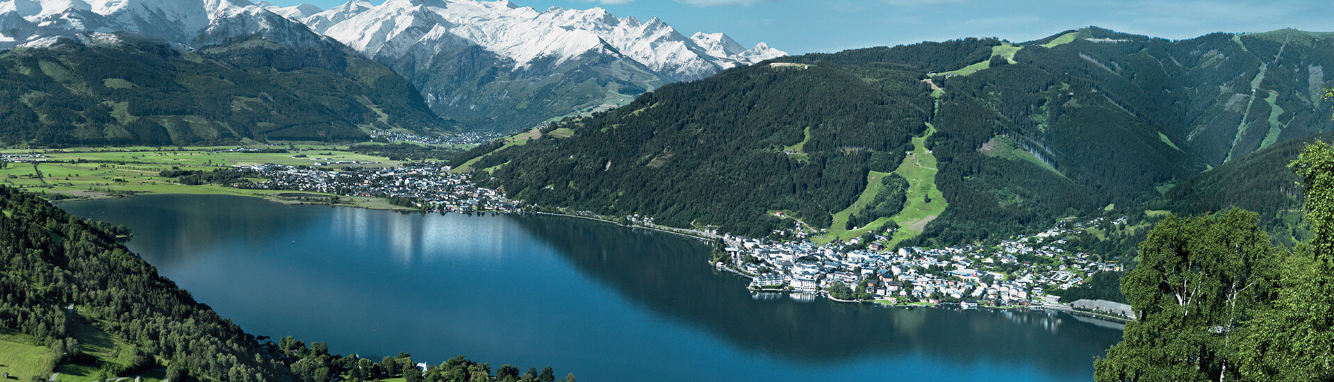 Panoramablick auf Zell am See und die Alpen mit schneebedeckten Bergen im Hintergrund.