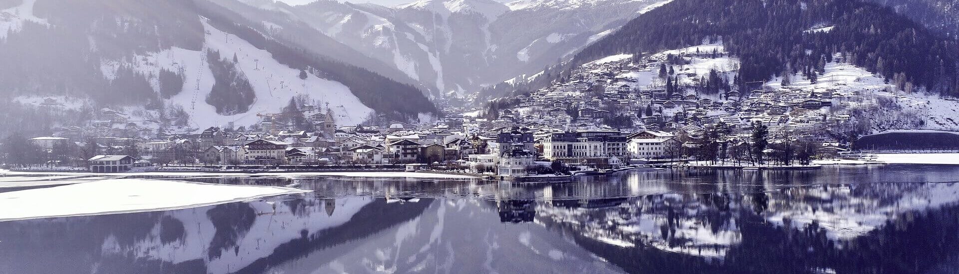 Panoramablick auf das verschneite Zell am See und die umliegenden Berge im Winter.