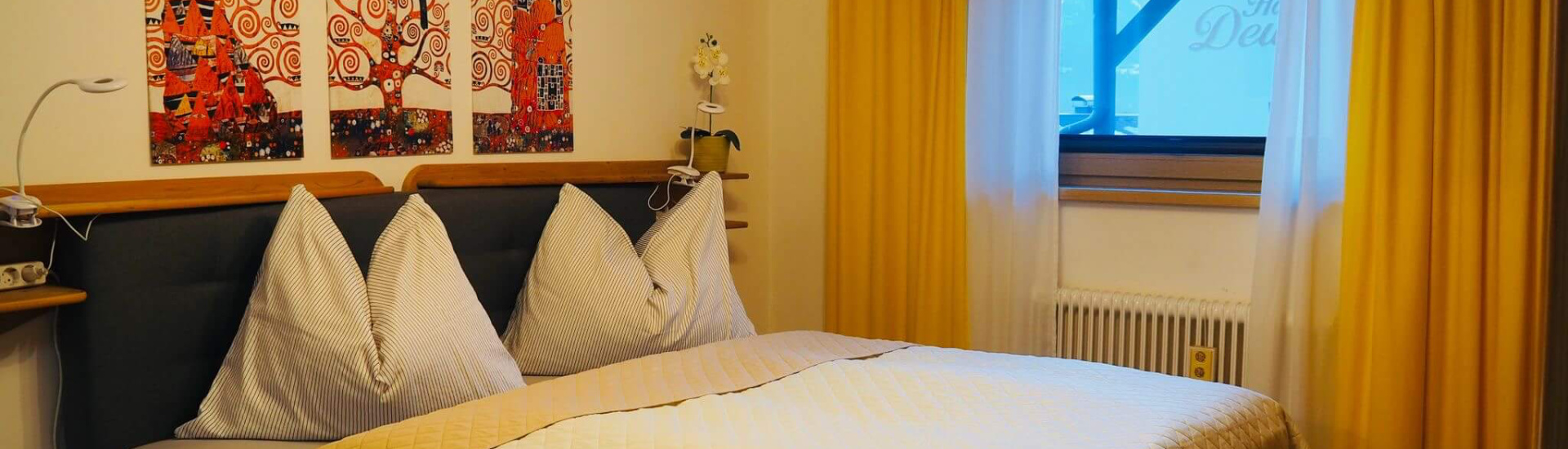 Gemütliches Schlafzimmer mit modernem Design, Blick auf kunstvolle Wandbilder und Fenster.